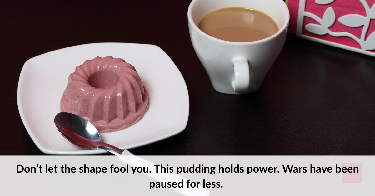 A chocolate gelatin pudding sits on a square white plate beside a spoon, next to a white mug of coffee on a dark table. The setup resembles a hospital tray dessert.